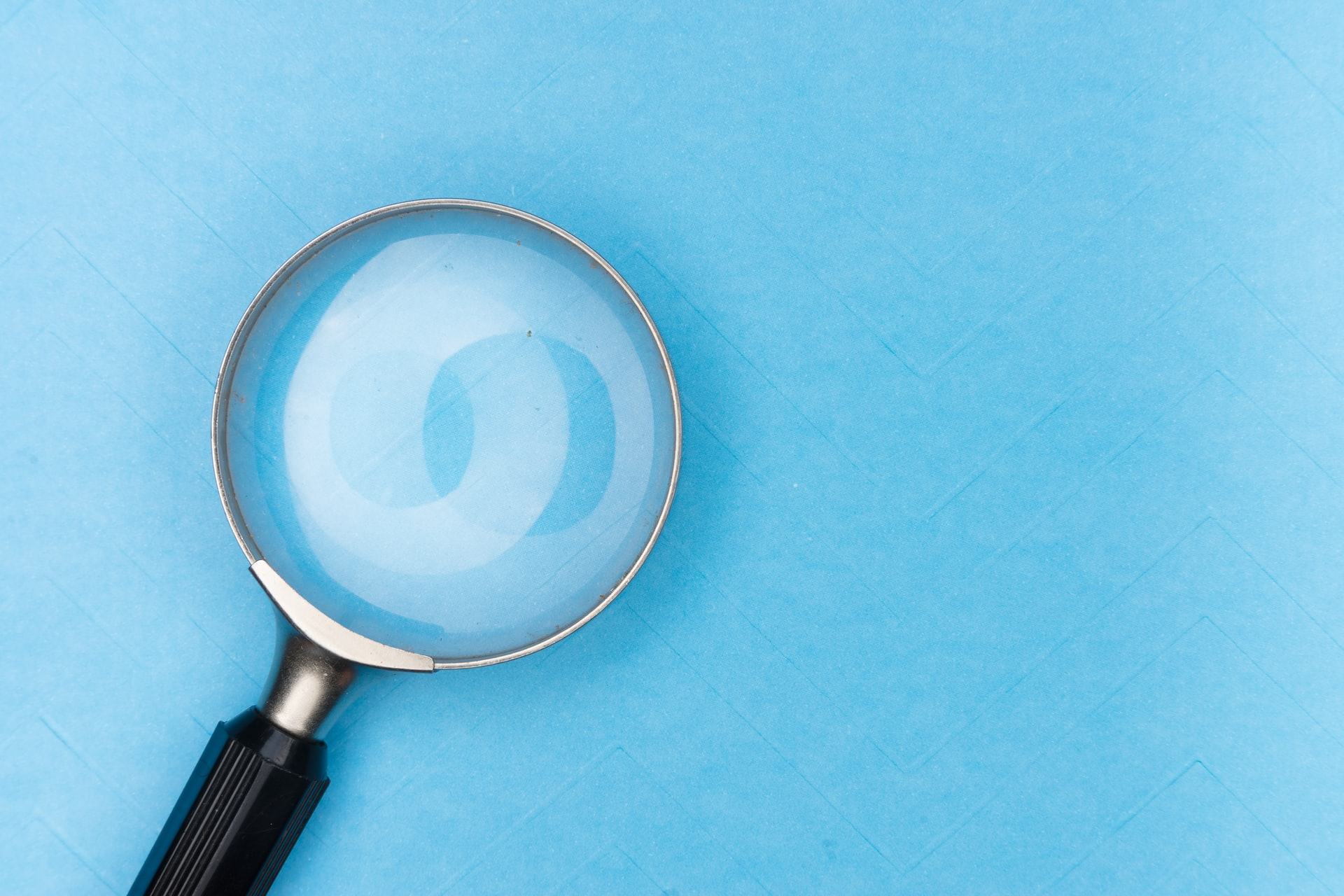 A magnifying glass on a plain blue background to symbolize the search bar on Google