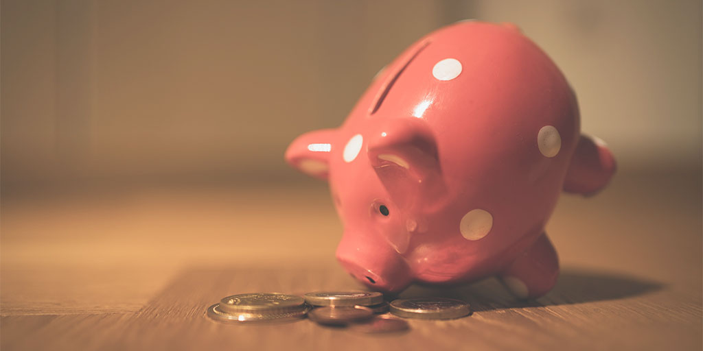 image of a toy piggy bank with its head down, resting on coins