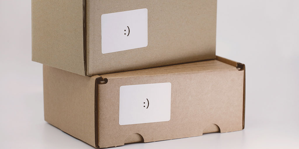 photo of two plain packaging boxes with a smiliey each on their name label