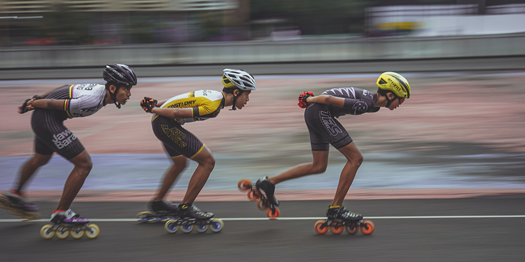 photo of three roller skaters in a single file, racing