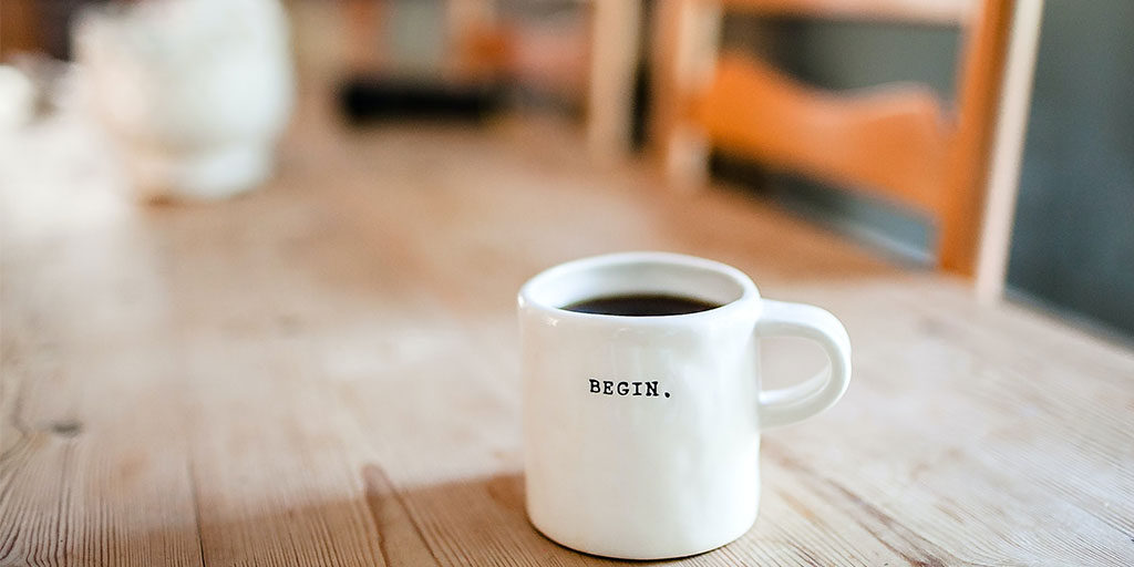 Black coffee in a mug that reads, begin.