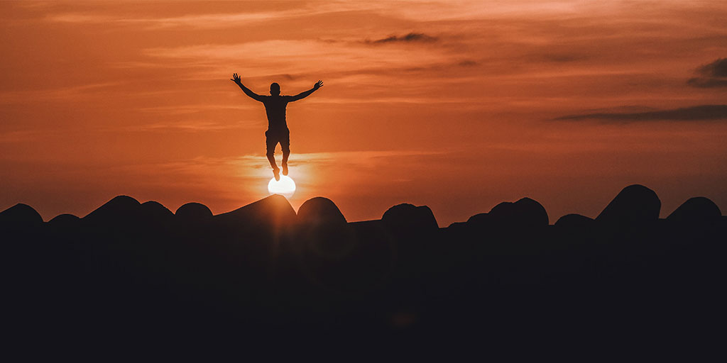 a person jumping high with the sunset in the background