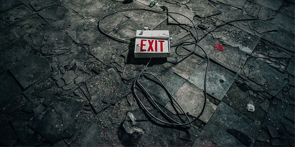 An exit sign on the ground with snapped wires around it