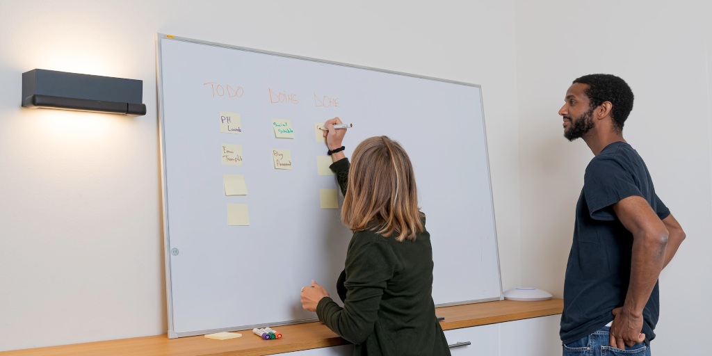 A woman is writing a marketing plan on a white board
